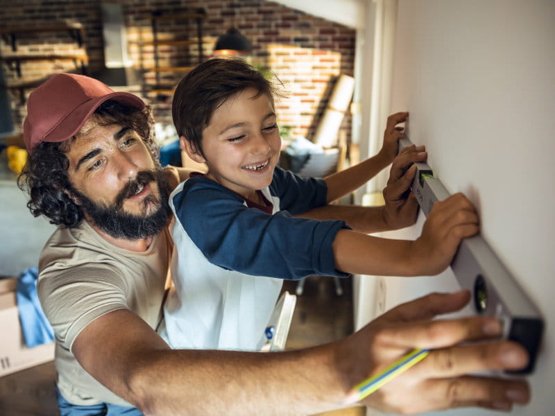 Père et enfant mesurent un mur ensemble avec un niveau à bulle