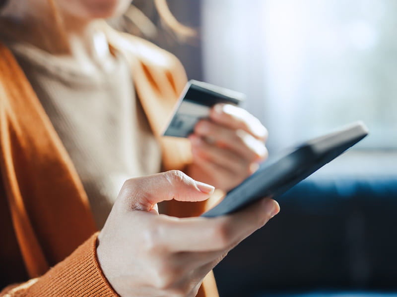 Personne tient un smartphone et une carte bancaire dans les mains lors d’un paiement numérique