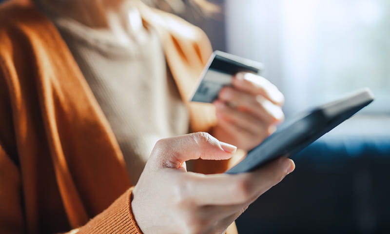 Personne tient un smartphone et une carte bancaire dans les mains lors d’un paiement numérique