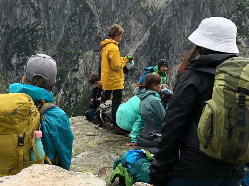 Des élèves avec des sacs à dos font une pause en montagne pendant un camp scolaire.