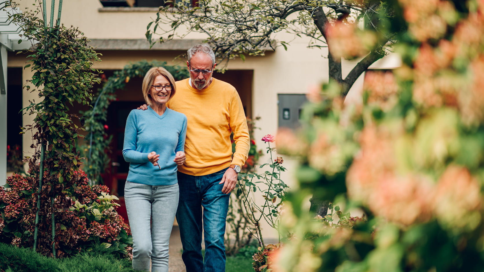 Couple âgé marche ensemble dans un jardin devant la maison
