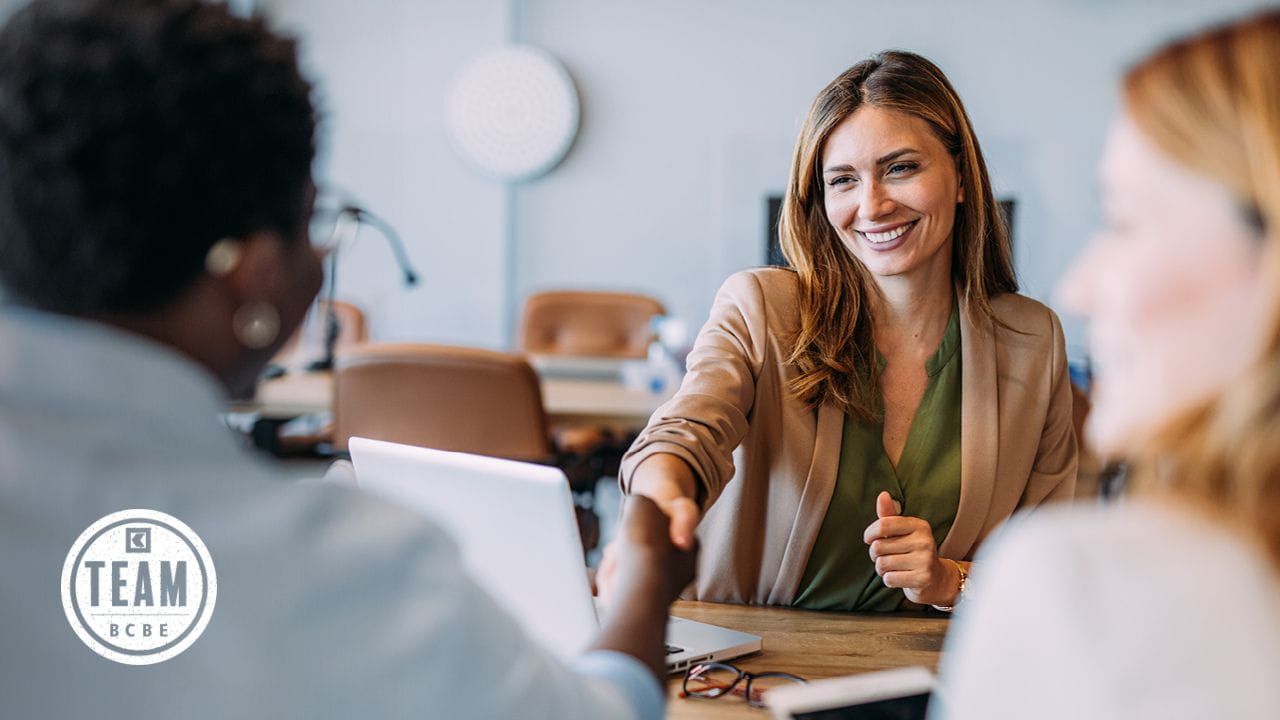 Conseillère à la clientèle serre la main d’une personne lors d’un entretien de conseil à table